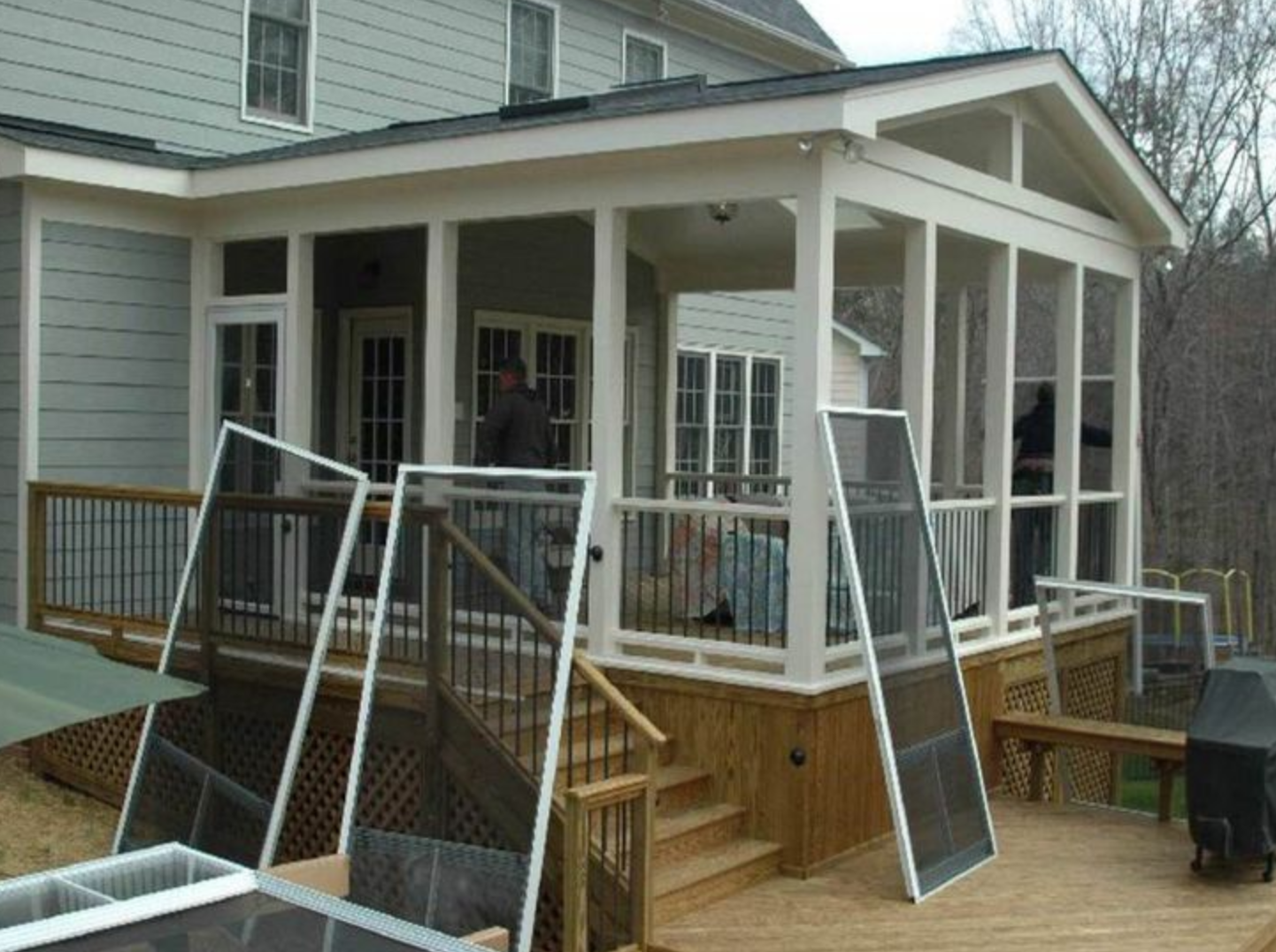 Man sweeping outdoor area near wooden building, emphasizing maintenance work.